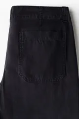 Pantalón de corte relajado confeccionado en tejido ripstop resistente. Presenta cierre con botón, bolsillos laterales al bies y bolsillos traseros de parche. Incluye costuras horizontales en las piernas y cordón ajustable en los bajos.
