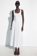 Vestido midi de corte corsetero color blanco, con escote redondo, tirantes finos y detalle de lazo en el delantero. Falda con frunces y cierre en la espalda con cremallera oculta.