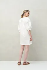 Vestido corto negro con bordado floral blanco, escote redondo con abotonadura frontal y mangas 3/4 abullonadas con pliegues en los hombros.