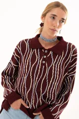 Buzo tipo polo de silueta relajada con cuello clásico y cartera con botones en el frente. Presenta un diseño tejido de ondas verticales en tonos bordó, celeste y crema.