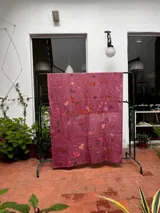 Mantel rectangular de lino color rosa con estampado de hojas y flores en tonos naranja, marrón y blanco.