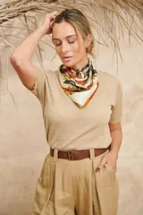 Pañuelo cuadrado de seda color beige con estampado floral en tonos naranja, marrón y negro.