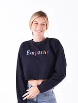 Buzo crop top de color azul oscuro con cuello redondo, mangas largas y estampa frontal con la palabra 'Empathy' en letras de colores.