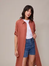 Vestido camisero largo de corte holgado, con cuello clásico, cierre frontal completo con botones y mangas tres cuartos.