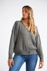 Cárdigan de tejido liviano con textura acanalada, cuello en V y cierre frontal con botones. Presenta mangas largas y un diseño clásico con detalle de grifa en cuero.