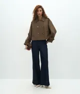 Trench coat corto de la marca Cortelle, confeccionado en una mezcla de algodón y poliéster. Presenta un diseño estructurado con cierre cruzado de botones, cuello clásico, mangas largas con trabillas en los puños y bolsillos frontales.