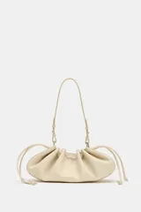 Mini bolso de hombro color crudo con diseño fruncido, textura granulada y cierre mediante cordones ajustables en los laterales. Cuenta con un asa fina de hombro.