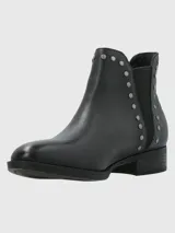 Bota corta de cuero negro con diseño de paneles laterales con textura tipo reptil y detalle de tachas metálicas plateadas a lo largo del empeine. Cuenta con un tacón bajo y suela de caucho.