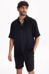 Bermuda negra de muselina con corte baggy, estilo deportivo y cordón ajustable en la cintura.