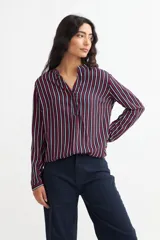 Blusa de viscosa con estampado de rayas verticales en azul marino, rojo y blanco, con cuello mao y mangas largas con puños abotonados.