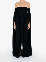 Vestido largo negro de silueta fluida con escote palabra de honor, cuerpo fruncido elástico y mangas largas caídas con paneles amplios de tejido.