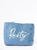 Bolso tipo tote de color azul con el logo de la marca Rusty estampado en el frente en color claro. Cuenta con dos asas superiores para llevar al hombro.