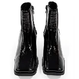 Bota corta de cuero vacuno color negro, con taco cuadrado de madera y punta cuadrada. Presenta cierre lateral interno y costuras visibles en el empeine.