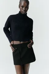 Falda pantalón de tiro medio en color blanco, con diseño minimalista y detalle de cinturón fino integrado con hebilla metálica. Cuenta con cierre lateral mediante cremallera oculta.