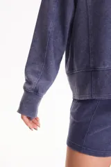 Buzo deportivo sin frisa color azul con efecto lavado, cuello redondo, mangas largas y estampa pequeña en el pecho con diseño de sol y texto.
