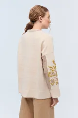 Sweater de punto color gris claro, confeccionado en lambswool. Presenta cuello redondo, combinación de puntos en el frente y bordados florales hechos a mano en las mangas.