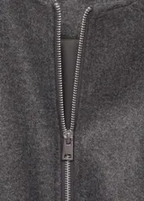 Chaqueta tipo bomber de color gris oscuro, con cuello redondo, cierre frontal de cremallera y diseño oversize. Presenta mangas largas con puños elásticos fruncidos y detalle fruncido en el bajo, además de dos bolsillos laterales.