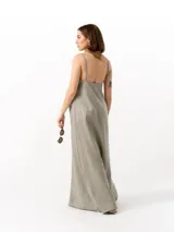 Vestido largo de lino en color beige, con escote recto, tirantes finos ajustables, cierre lateral y bolsillos frontales tipo parche.