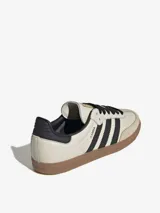 Zapatillas Adidas Samba OG de cuero color crema con detalles en negro y suela de goma marrón.
