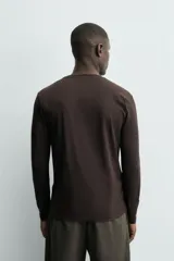 Camiseta slim fit de manga larga y cuello redondo, confeccionada en tejido de algodón elastizado de color marrón oscuro.
