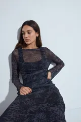 Top de manga larga confeccionado en tejido de malla semitransparente con estampado de cuadros escoceses en tonos marrones, negros y blancos. Presenta un diseño entallado con cuello redondo y terminaciones con efecto ondulado en los puños.