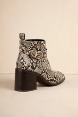 Botas de caña baja color negro, con taco cuadrado, punta fina y detalle de tira con textura de piel de reptil y hebilla metálica.