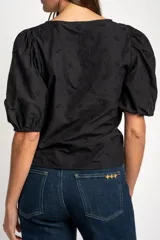 Blusa negra de algodón con diseño bordado sutil, escote en V y cordón ajustable fruncido en el centro del frente. Mangas cortas abullonadas.