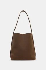Bolso de hombro tipo saca, de diseño minimalista y estructura flexible. Cuenta con asa de hombro, cierre mediante clip metálico y compartimento interior extraíble con cremallera.