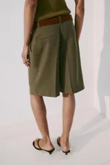 Bermuda fluida color verde militar con pinzas delanteras, tiro medio y trabillas en la cintura. Incluye un cinturón marrón de gamuza con hebilla metálica dorada.