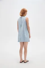 Vestido corto de jean blanco con tirantes anchos, cuello redondo, corte holgado y bolsillos laterales.