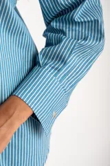 Camisa celeste con rayas verticales blancas, de corte oversize y manga larga.