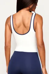Monopieza deportiva color azul marino y blanco, con efecto bicolor que simula la combinación de una musculosa y calzas. Presenta dos tiras laterales en celeste y breteles medios.