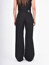 Jean de corte recto y tiro alto, color negro, con diseño de ojales metálicos distribuidos por toda la prenda.