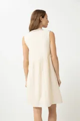 Vestido corto color crema, de corte recto y sin mangas, con bordados en el escote, sisas y ruedo.