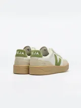 Championes Veja modelo V-90, color blanco con detalles en verde y beige, suela de goma marrón y la característica 'V' de la marca en los laterales.