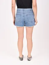 Short de jean azul claro, tiro alto, con roturas y terminación deshilachada en el ruedo.