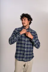 Camisa de manga larga confeccionada en tejido de franela con estampado de cuadros en tonos azul marino y verde. Presenta cuello abotonado, cierre frontal con botones y un bolsillo en el pecho con el logo bordado de la marca.