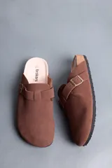 Sandalias estilo zueco de hombre, color marrón, con capellada cerrada, tira con hebilla ajustable lateral y suela de corcho y goma.