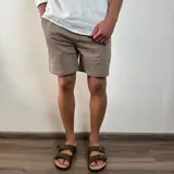 Bermuda de corte recto en color beige, confeccionada en tejido simil lino. Presenta cintura elástica con cordón de ajuste y bolsillos laterales.