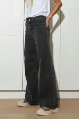 Jean de pierna ancha color gris oscuro, con cintura alta, bolsillos delanteros y traseros con detalle de trenzado, y cinturón de soga.