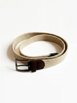 Cinto de tela trenzada color beige con detalles de cuero marrón y hebilla metálica rectangular.