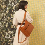 Cartera mochila negra de símil cuero con diseño convertible, bolsillo frontal con cierre y tirador, apertura superior doble y correas ajustables.