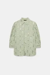 Camisa de corte recto en color verde claro con estampado de rayas verticales y detalles de lentejuelas brillantes. Presenta cuello solapa, cierre frontal con botones y mangas tres cuartos.