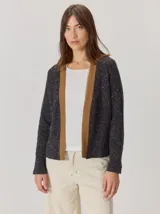 Saco abierto de punto con textura jaspeada en color gris oscuro, con bordes frontales en contraste color marrón. Presenta mangas largas y un corte recto.