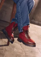 Botas de caña media con plataforma, confeccionadas en tweed a cuadros rojos y negros, con detalles en cuero marrón y cordones marrones.