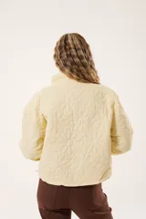 Campera color manteca con diseño acolchado de flores, cuello alto, cierre frontal con cremallera y bolsillos laterales.