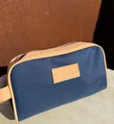 Neceser de lona verde con detalles en cuero color beige y etiqueta con logo de la marca Sierra Mora.