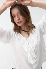 Blusa verde militar de manga larga con volados en el escote en V y lazos para atar al frente.