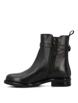 Bota baja de cuero color negro, con caña media, puntera redonda, elástico lateral y tira decorativa con hebilla metálica.