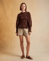 Blusa marrón de muselina de algodón con cuello alto fruncido, mangas largas abullonadas con puños elásticos y elástico en la parte delantera y trasera.